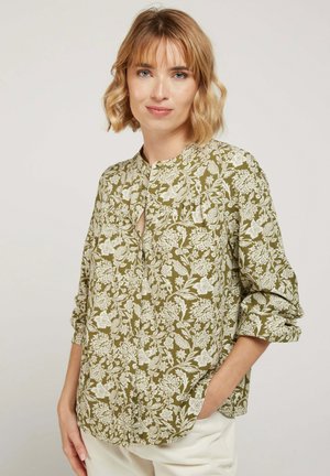 Blouse à motifs floraux en vert olive, présentant un design sans col, une patte de boutonnage et des manches retroussées, fabriquée en tissu léger.