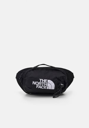 Kompaktowa czarna saszetka na talię z białym logo "The North Face" i regulowanym paskiem na jednolitym tle.