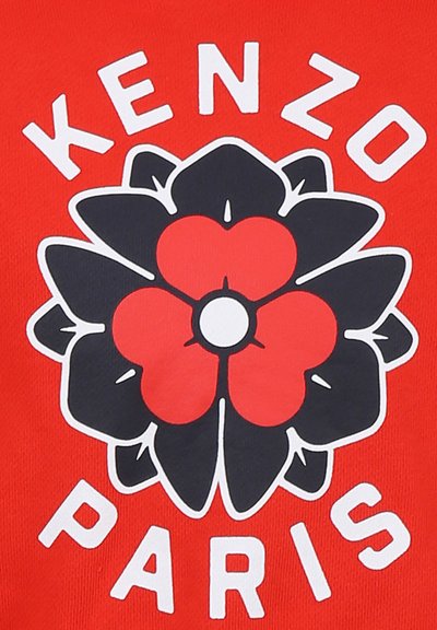 T-shirt rouge avec un grand motif de fleur noire agrémenté de rouge et de blanc, et le texte "KENZO PARIS" en lettres blanches en gras.