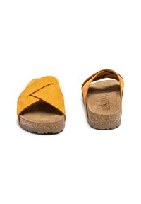 Gelbe Wildledersandalen mit gekreuzten Riemen, Korkfußbett und strukturiertem, braunem Außensohle. Offenes Design an der Rückseite mit weichem Innenfutter.