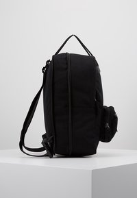 Svart ryggsäck med rektangulär form, tillverkad av tyg, utrustad med en sidoficka med dragkedja, justerbara remmar och en platt topp.