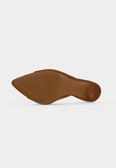 Semelle de chaussure pour femme marron à bout pointu, talon plat, vue de dessous sur un fond clair uni.