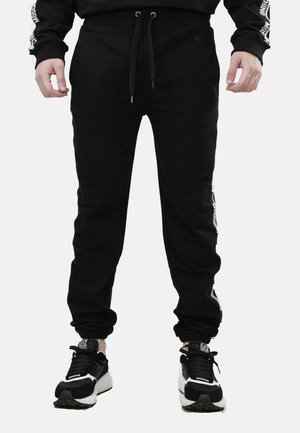 Pantaloni sportivi neri con gamba svasata, vita con coulisse regolabile e accenti bianchi stampati sui lati. Realizzati in un tessuto morbido.