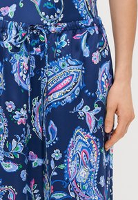 Karinio mėlynumo audiniai kelnės su paisley raštu rožinės, žalios ir baltos spalvų. Elastinga juosmens juosta su raišteliu.