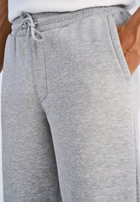 Grijze joggingbroek gemaakt van zacht, gestructureerd materiaal met een elastische tailleband en trekkoord. Voorzien van zijzakken en een losse pasvorm.