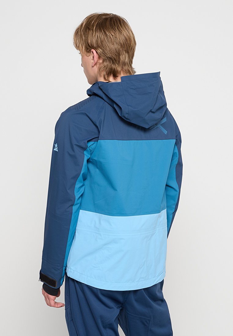 Kurtka z kapturem w ciemnoniebieskie i jasnoniebieskie bloki kolorystyczne, o teksturowanym wykończeniu i regulowanymi mankietami, prezentująca nowoczesny design.