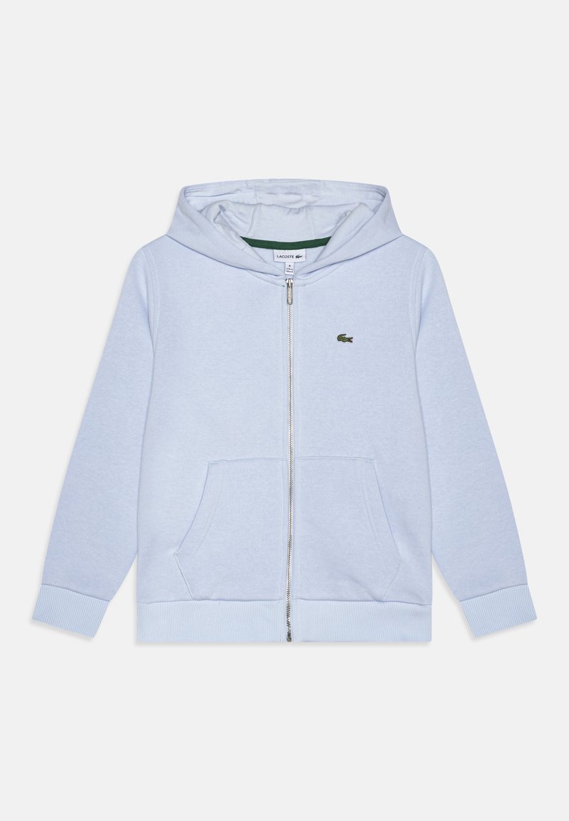 Felpa con zip di colore azzurro chiaro, dotata di tasca a marsupio, polsini a costine e logo Lacoste in tonalità simile. Tessuto morbido con una texture liscia.