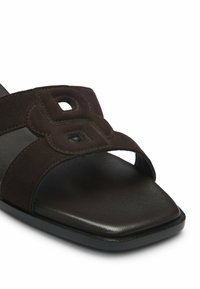 Sandale à glissière en daim marron avec bout ouvert, semelle carrée et design décoratif ajouré sur la bride.