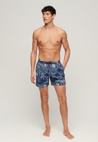 Heren zwembroek in marineblauwe stof met een wit bloemenpatroon, elastische tailleband met trekkoord en zijzakken.