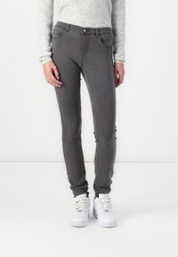 Gray skinny jeans featuring a five-pocket design, subtle fading, and a button closure. Paired with white sneakers and a light sweater.