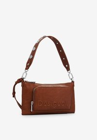 Borsa a tracolla in pelle marrone con finitura texture, chiusura con zip e tracolla con borchie. Presenta il logo impresso sul fronte.