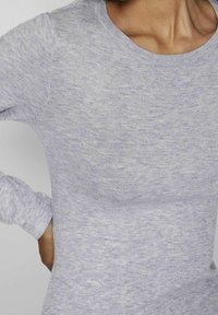 Haut à manches longues gris en tissu côtelé, avec un col rond et une coupe ajustée, présentant une texture subtile.