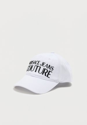 Bela baseball kapa s ukrivljenim robom, na sprednji strani črno vezen napis "VERSACE JEANS COUTURE", na preprostem svetlem ozadju.