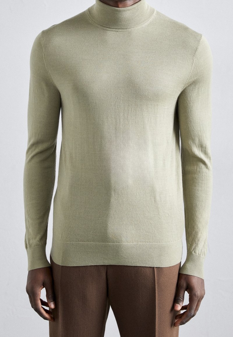 Světlý zelený rolák z měkkého pleteného materiálu. Přiléhavý střih s dlouhými rukávy, žebrovanými manžetami a lemem.