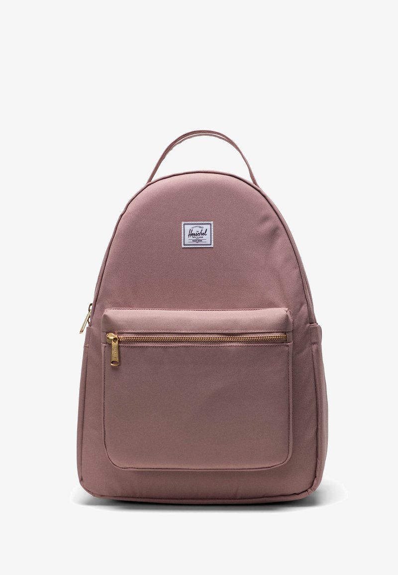 Mochila de tela rosa con un diseño redondeado, asa superior única, bolsillo frontal con cremallera, herrajes dorados y un parche con el logo en la parte frontal.
