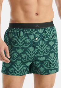 Gröna mönstrade boxershorts med blommig design, elastisk midjeband med logotyp och knäppt frontslå.
