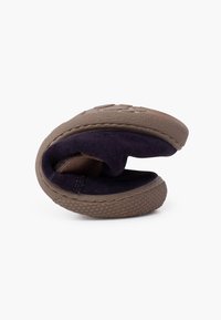 Soft brown slipper, flexible design, with a navy suede interior. Rubber outsole with textured grip and stitched accents on edges.