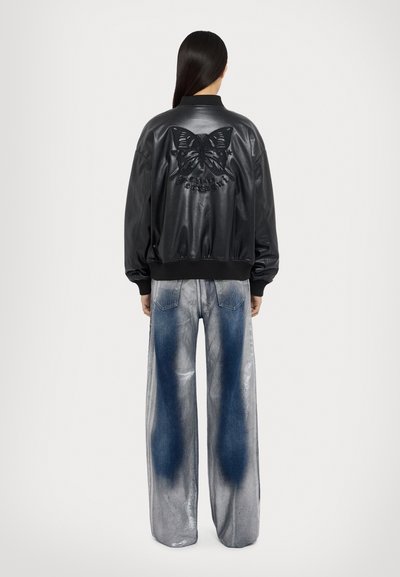 Svart läder bomberjacka med ribbstickade ärmar, med en upphöjd fjärilsdesign på baksidan. Kombinerad med vida metalliska denimjeans.