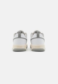 Weiße und graue Sportschuhe mit strukturierten Einsätzen, Stoffakzenten und einem gepolsterten Kragen, die ein auffälliges Logo an der Ferse tragen.