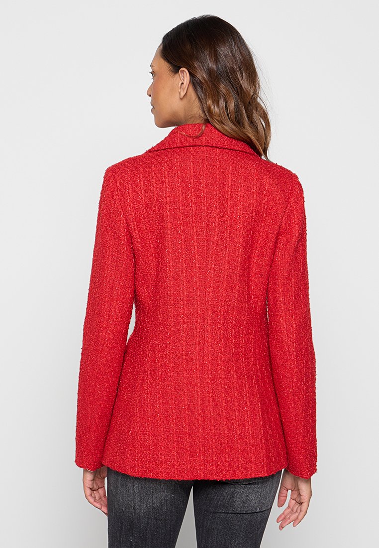 Blazer rosso texture con colletto a rever, vestibilità sartoriale e maniche lunghe, caratterizzato da un motivo a trama fine. Vista posteriore mostrata.