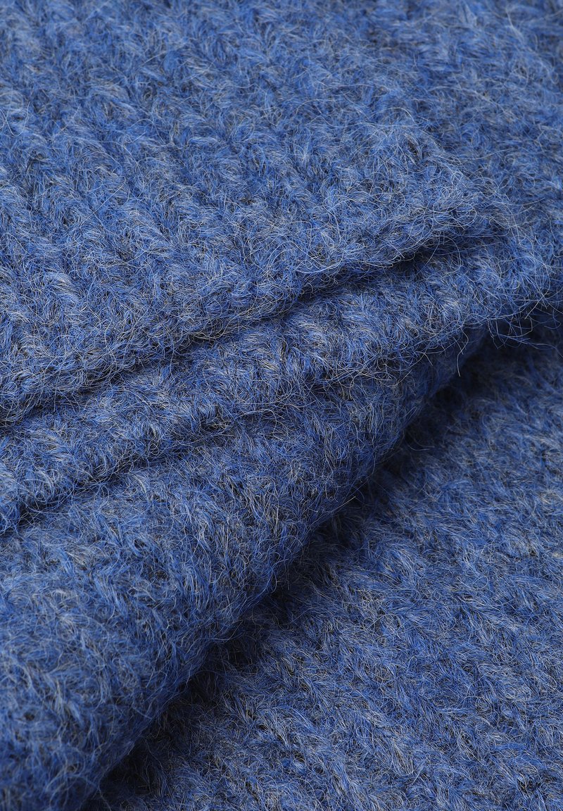 Niebieska tekstura materiału o puszystym wyglądzie, z plecionym wzorem w różnych odcieniach niebieskiego i miękkimi, luźnymi włóknami.