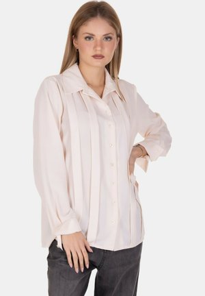 Blusa rosa chiaro a maniche lunghe con chiusura a bottoni, caratterizzata da pieghe verticali e un colletto classico, realizzata in un tessuto morbido e liscio.