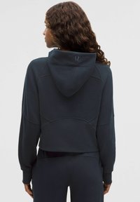 Granatowa krótka bluza z kapturem, z logo na plecach, teksturowana tkanina i dopasowane mankiety. Gładkie wykończenie, minimalne szwy.