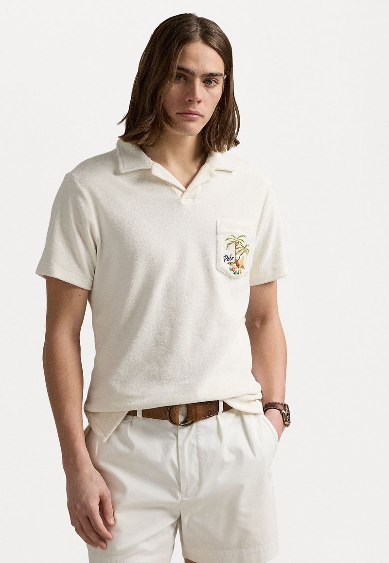 Bombažna polo majica v kremni barvi z teksturiranim zaključkom, kratkimi rokavi in prsno žepom z vezenim motivom palme.