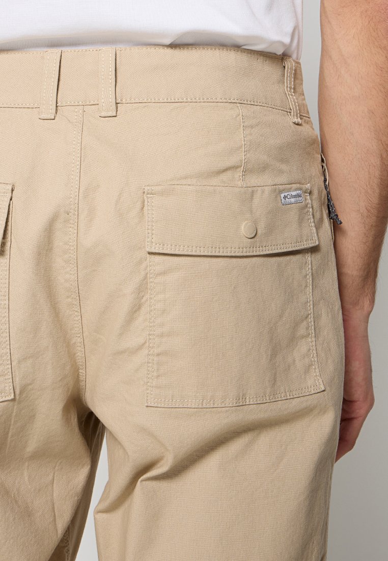 Pantalons cargo beiges avec deux poches arrière à rabat boutonné et une étiquette tissée. Le tissu a une finition texturée et une coupe droite.