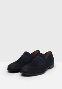 Marineblaue Wildlederslipper mit einer genähten Zehenpartie, im Slip-On-Stil und einer flachen schwarzen Gummisohle. Verfügt über eine glatte, strukturierte Oberfläche.