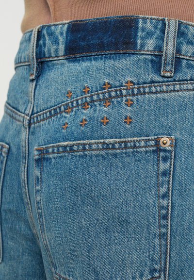 Denimshorts i en blekt ljusblå färg, med bruna broderade detaljer på bakfickan och en något avvikande färg på midjebandet.