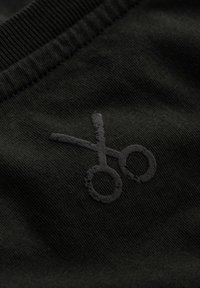 Tessuto nero con una consistenza morbida con logo a forbici nero. Il design include un collo a coste e una superficie liscia e priva di decorazioni.