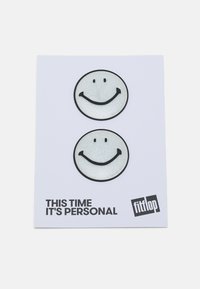  Dois emblemas circulares de rosto sorridente, brancos brilhantes com contornos pretos, sobre um cartão branco simples com o texto "Desta vez é pessoal" e "fitflop."