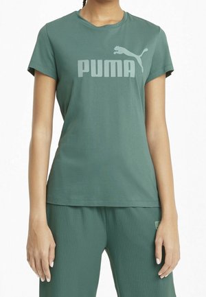 Person wearing green Puma t-shirt and ribbed matching pants, standing with arms relaxed by sides against white background.