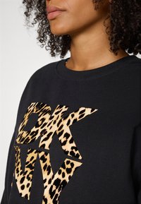 Zwarte sweatshirt met gedurfde DKNY-logo en luipaardprint-details, ronde halslijn en geribbelde manchetten. Zachte textuur.