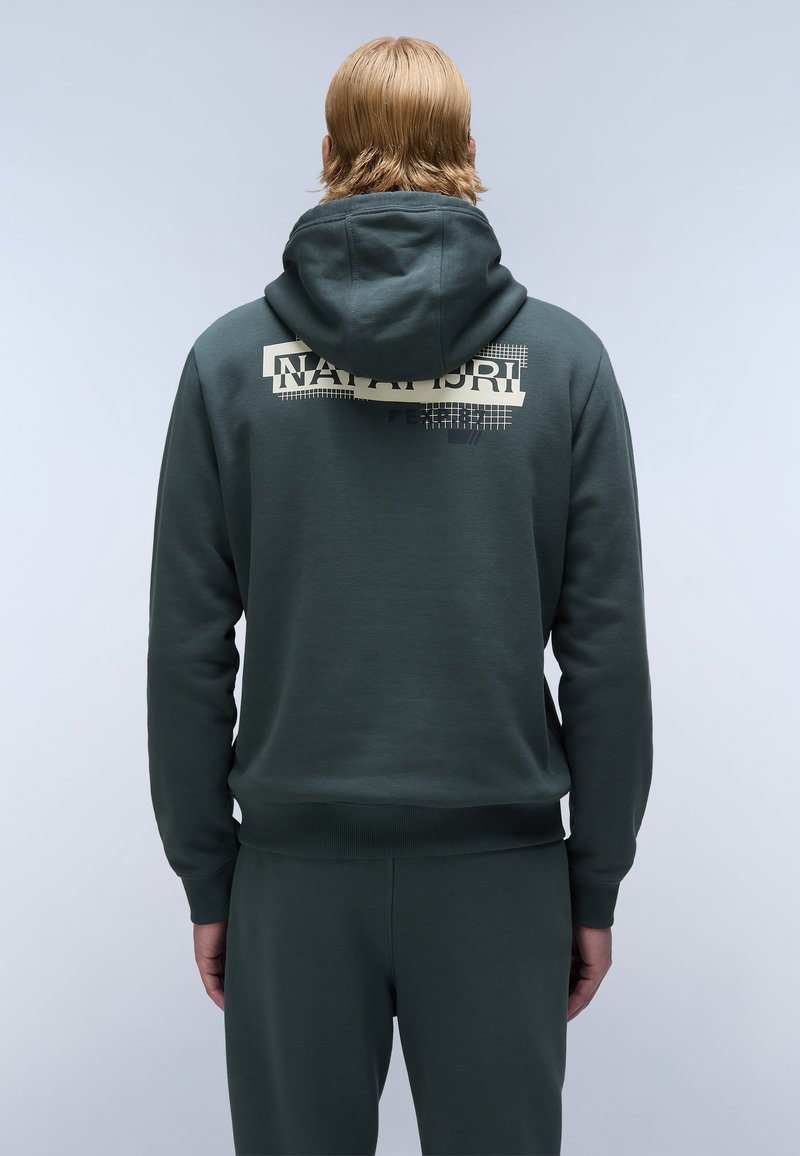 Donkergroene hoodie met een grote grafische print op de achterkant, met "NAPAPIJRI" en geometrische patronen. Gemaakt van zachte, gestructureerde stof.