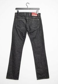 Jeans in denim grigio scuro con gambe dritte, cuciture visibili, due tasche posteriori e un'etichetta in pelle rossa in vita. Appesi a un gancio nero.