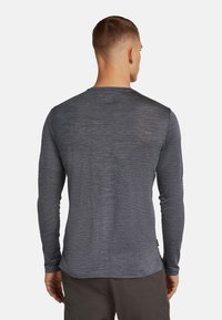 Langarmshirt in dunkelgrau, gefertigt aus weichem, strukturiertem Stoff. Rundhalsausschnitt und eine taillierte Passform mit einer leichten Saumkrümmung.
