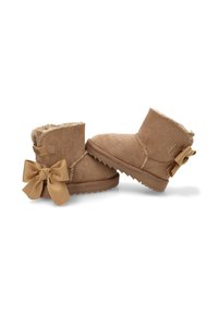 Botas de tobillo de ante beige con un suave forro interior, detalles de costura y un gran lazo en el talón. Suela de goma texturizada.
