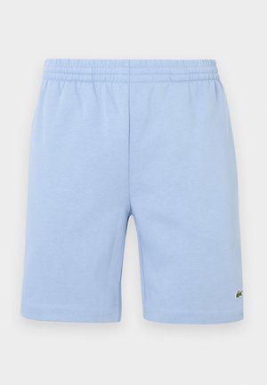 Pantalones cortos de algodón con cintura elástica de color azul claro, con un pequeño logo bordado de cocodrilo verde en la parte inferior de la pierna derecha.