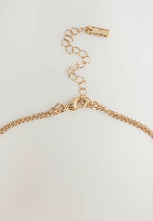 Kuldse tooniga kett, millel on peen linkide disain, sõrmeluku sulgur ja reguleeritav kett ringikujuliste linkidega.