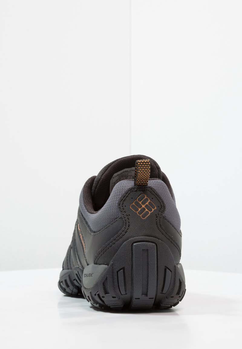 Czarno-szare buty sportowe z teksturowanym materiałem, solidną podeszwą i pomarańczowymi akcentami. Zawierają wyściełany zapiętek i pętelkę do łatwego zakładania.