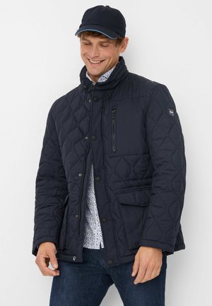 Marineblauwe gewatteerde jas met een hoge kraag, knoopsluiting aan de voorkant, een ritszak op de borst en twee klepzakken. Lichtgewicht polyester materiaal.