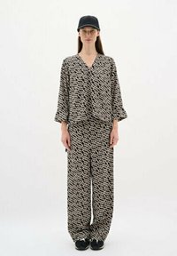 Black and white patterned loungewear set with a relaxed fit. The top features a V-neck and 3/4 sleeves, paired with loose, wide-leg pants.