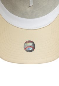 Bežs beisbola cepure ar baltu priekšējo paneļu, izliekto malu un acs aizmuguri. Iekļauts apaļš MLB uzlīme cepures apakšpusē.