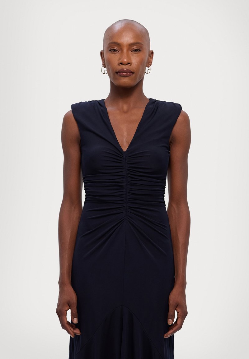 Navy blue sleeveless dress with a V-neck, featuring ruched detail at the bodice and a flowing silhouette, made from soft, stretchy fabric.