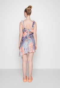 Robe courte sans manches avec un motif floral multicolore, des bretelles froncées et un dos ouvert. Fabriquée en tissu léger et fluide.
