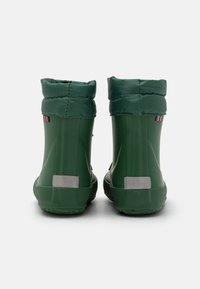 Zöld vízálló bakancs sima felülettel, hajtható szegéllyel, fényvisszaverő részletekkel és mintás talppal a jó tapadásért.