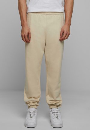 Beiga sweatpants i mjukt tyg, med elastisk midja och avslutade anklar, tillsammans med vita sneakers.