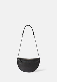 Black half-moon leather crossbody bag with adjustable strap and gold zipper closure on a plain light background.